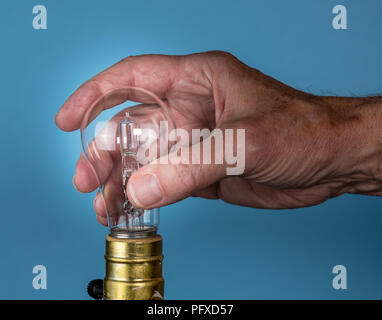 Senior man hand unscrewing the halogen bulb Stock Photo