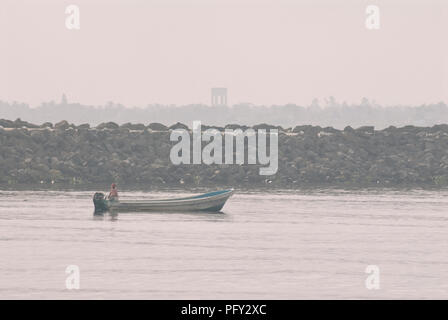 COATZACOALCOS, VER/MEXICO - AUG 18, 2018:  A fisherman fishes on a motorboat at the river mouth during a hazy day Stock Photo