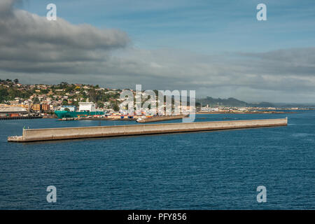 Burnie, Tasmania, Australia - December 15, 2009: The harbor with green ferry as seen from the blue sea. Long defensive sea wall uip front. Town built  Stock Photo