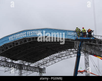 Three workers in a cherry picker assisting in the huilding of a stage for a music festival Stock Photo