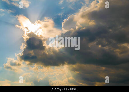 bright sun illuminating the clouds from behind with light rays Stock Photo