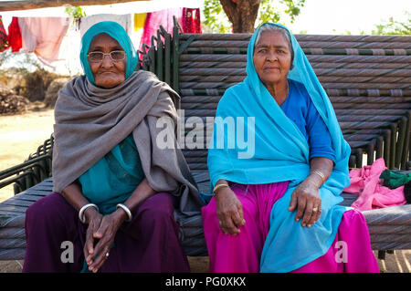 HAMPI, INDIA - FEBRUARY 14, 2015: Two elderly Indian women dressed in traditional clothes and head scarf sitting on stacked benches. Stock Photo