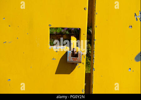 Padlock on bright yellow metal gates Stock Photo