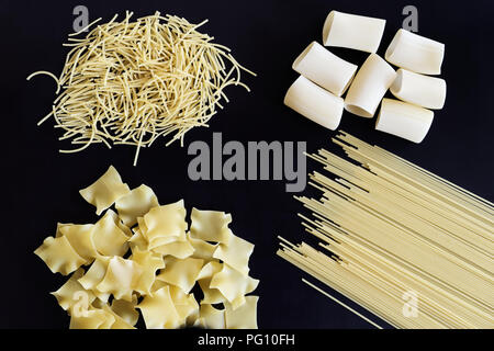 Four different types of pasta are laid out on black background Stock Photo