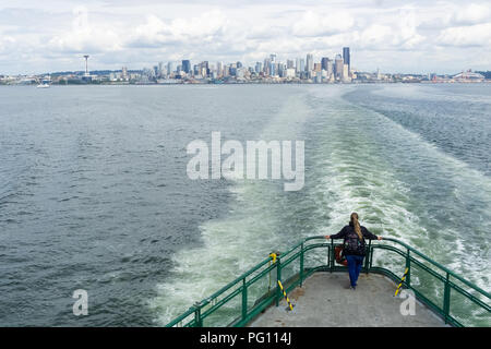 Woman on the Bainbridge Island ferry boat tail deck watching at the Seattle Skyline, Puget Sound, Washington state, USA. Stock Photo