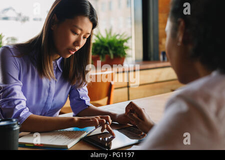 Two graphic designers sitting at a table, working on digital tablet Stock Photo