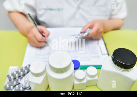 Close-up view of female doctor hand holding pills pack and writing prescription. Healthcare, medical and pharmacy concept. Stock Photo
