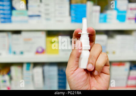 Hand holding digital thermometer at the pharmacy on shelves Stock Photo