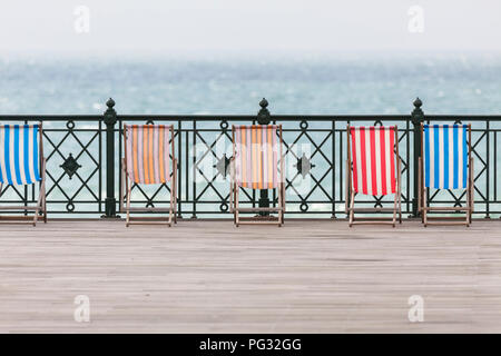 Hastings, East Sussex, UK. 23rd Aug, 2018. Empty colourful deckchairs sit on the hastings pier on a breezy day. © Paul Lawrenson 2018, Photo Credit: Paul Lawrenson / Alamy Live News Stock Photo