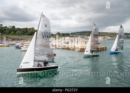 Lyme Regis, Dorset UK 23rd August 2018. Merlin Class dingies sail right into a crowded harbour  in gusty winds after a days racing competition at the National Sailing Championships. Credit: Julian Eales/Alamy Live News Stock Photo