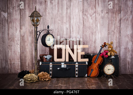 Composition in retro style, old suitcases, a lantern with a clock, a violin and a word one Stock Photo