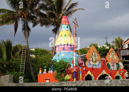 Very colorful Hindu temple in La Reunion, France with palm trees blowing in the wind Stock Photo