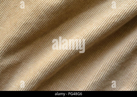 Texture of Soft Velvet Fabric with Folds Closeup. Texture of Beige Velvet Clothes. Textile Fabric of Corduroy as Background Stock Photo