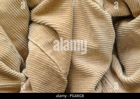 Texture of Soft Velvet Fabric with Folds Closeup. Texture of Beige Velvet Clothes. Textile Fabric of Corduroy as Background Stock Photo