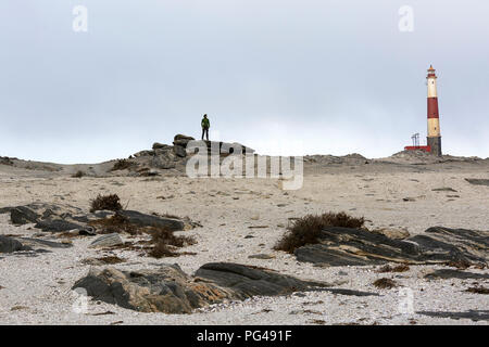 Woman standing on a rock by the Diaz Point Lighthouse, near Lüderitz, Diamond Coast Nature Reserve, Karas, Namibia Stock Photo