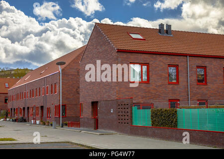Modern neigborhood with brown brick row houses and red elements. Stock Photo