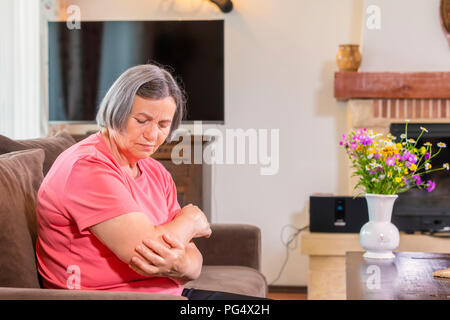 Senior woman suffering from pain in hand at home. Old age, health problem and people concept Stock Photo