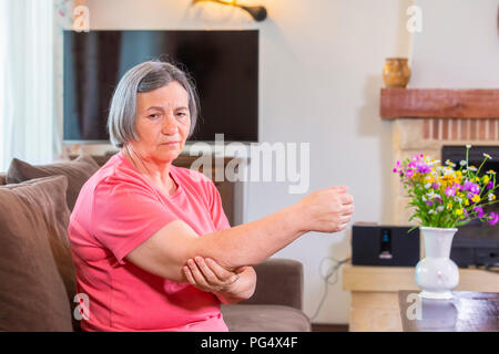 Senior woman suffering from pain in hand at home. Old age, health problem and people concept Stock Photo