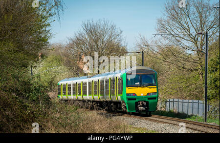 Class 321 passenger train in London Midland livery travelling along track on the Abbey Line, England.