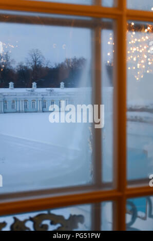 A view of the winter courtyard through the frosty window, the reflection of the shining chandelier in the glass. Stock Photo