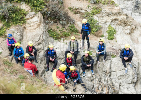 Holidaymakers listening to a safety talk by coasteering instructors on The Headland in Newquay, Cornwall. Stock Photo