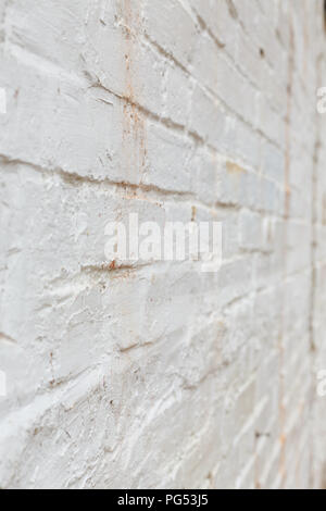 Detail of old brick wall painted white and distressed, peeling and stained. Ideal for grunge background texture Stock Photo