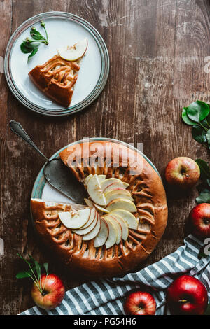 flat lay with piece of homemade apple pie, cake server and fresh apples on wooden surface Stock Photo