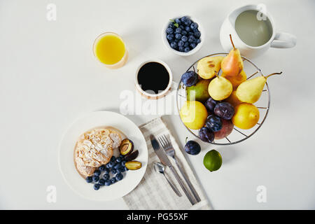 top view of croissant, cup of coffee and glass of juice for breakfast on white surface