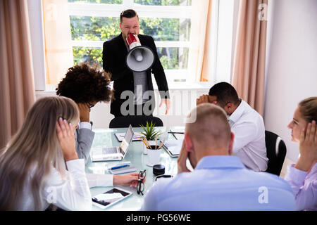 Angry Businessman Shouting At His Colleagues Through Megaphone Stock Photo