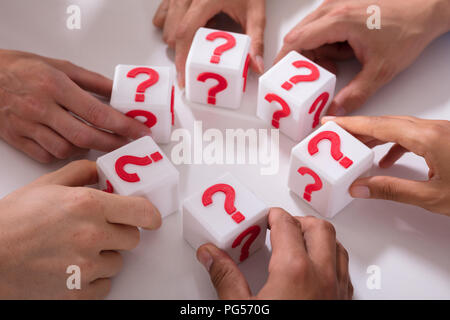 Close-up Of Businesspeople Holding Cubic Blocks With Red Question Mark Sign Stock Photo
