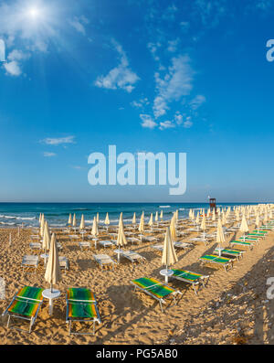 Sunshiny paradise white sandy beach with sunshades and sunbeds (Salento, south Italy). The most beautiful sea sandy beach of Apulia. Stock Photo