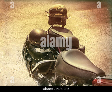 Two crash helmets for him and her on the back of a classic motorbike. Old Photographic Effect. Stock Image Stock Photo