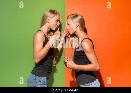 Angry women. Aggressive women standing isolated on trendy studio background. Female half-length portrait. Human emotions, facial expression concept. Front view. Stock Photo