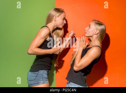 Angry women. Aggressive women standing isolated on trendy studio background. Female half-length portrait. Human emotions, facial expression concept. Front view. Stock Photo
