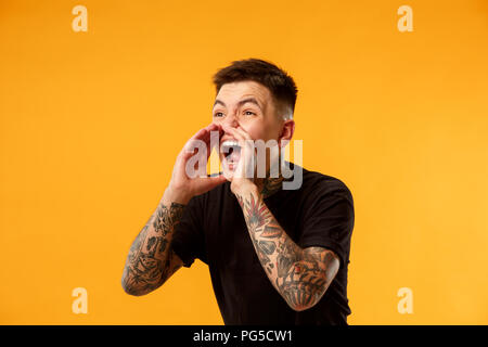 Do not miss. Young casual man shouting. Shout. Crying emotional man screaming on studio background. male half-length portrait. Human emotions, facial expression concept. Trendy colors Stock Photo