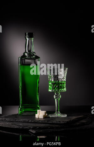 close-up shot of glass and bottle of absinthe with sugar cubes on dark background Stock Photo