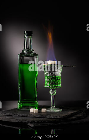 close-up shot of spoon with sugar cubes over burning absinthe in glass on dark background Stock Photo