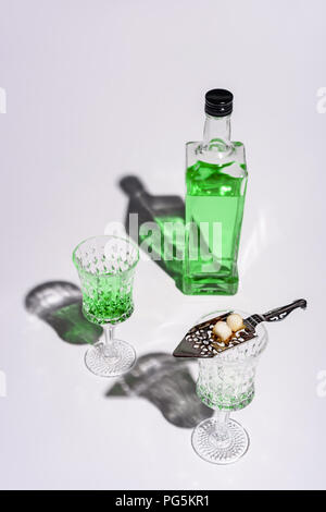 crystal glasses with absinthe spoon and bottle of absinthe on white Stock Photo