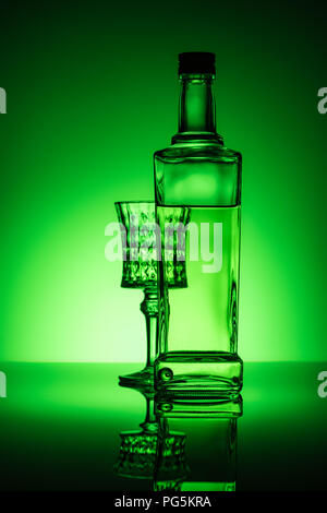 bottle of absinthe with lead glass on mirror surface and dark green background Stock Photo