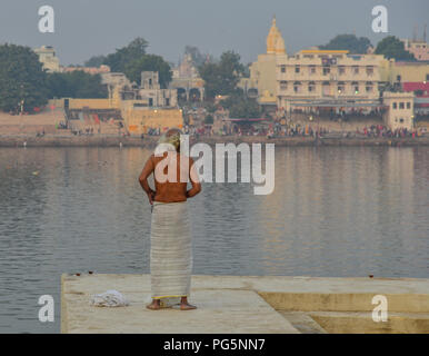 A man praying in front of Pushkar Lake. Pushkar is a pilgrimage site for Hindus and Sikhs, located in State of Rajasthan. Stock Photo