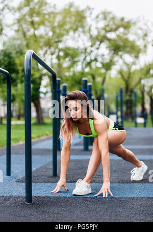 Young woman stretching on the sports ground in the park. Stock Photo