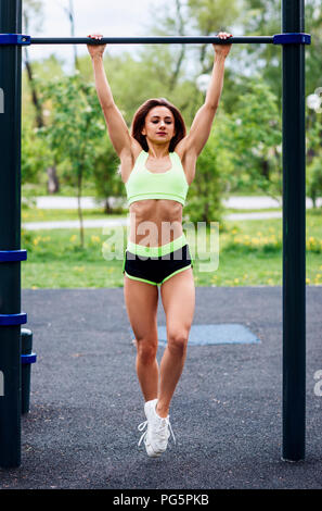 Woman pull-ups herself up on bar on sports ground in park Stock Photo -  Alamy