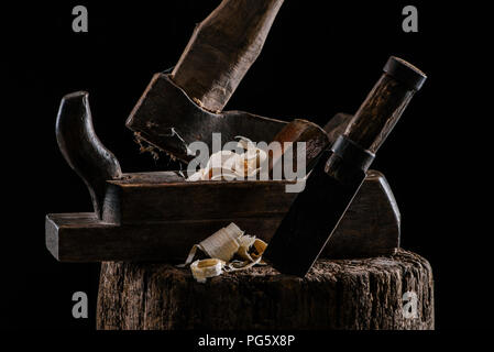 close up view of woodworker plane, axe and chisel carpentry tools on stump isolated on black Stock Photo