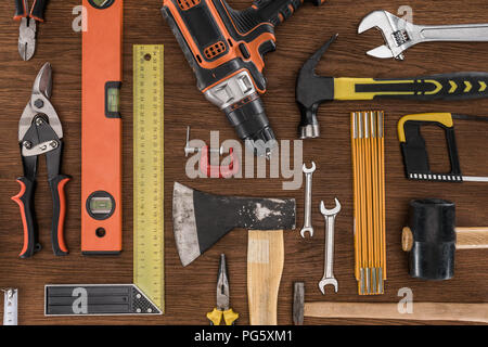 top view of axe, electric drill, spirit level, hammers and various tools on wooden table Stock Photo