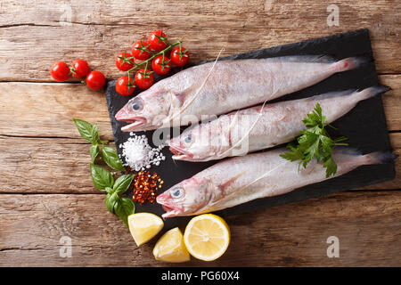 Raw Mediterranean Phycis phycis, or forkbeard fish for cooking with spices, vegetables ingredients close-up on the table. horizontal top view from abo Stock Photo