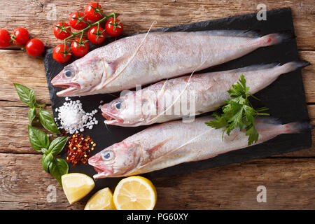 Phycis phycis, the forkbeard with spices, vegetables ingredients close-up on a table. horizontal top view from above Stock Photo