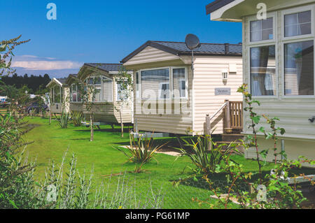 Static caravans on a camp site with flowers and bushes in Norfolk, England, UK Stock Photo