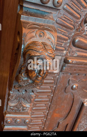 A head carved out of wood, part of a wooden cabinet in Bamburgh Castle, Northumberland, England, UK Stock Photo