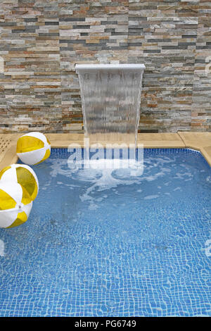 Modern small swimming pool with artificial waterfall Stock Photo