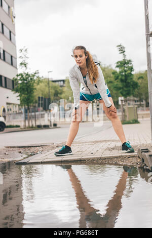 Sportive young woman standing at puddle Stock Photo